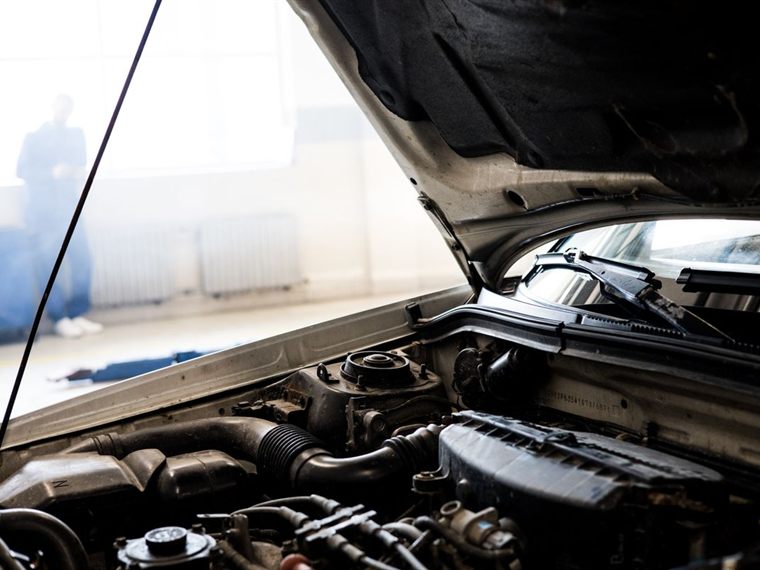 Open car hood showing the engine bay in a service garage